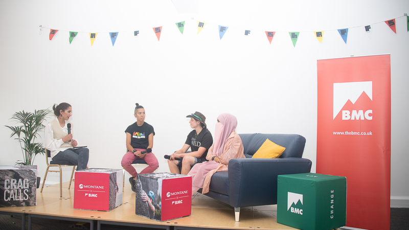 Four speakers sit on a sofa on a stage with the BMC banner behind them