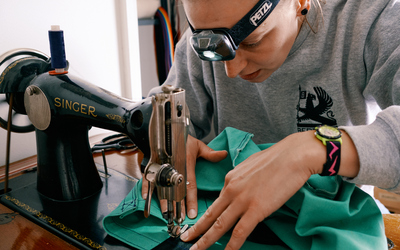 Becky Kirby of Sheffield Clothing repair leans over an old singer sewing machine as she fixes a piece of clothing