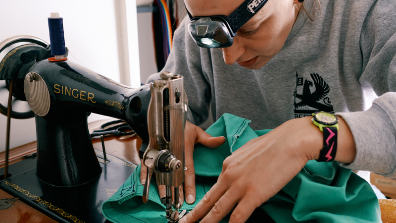 Becky Kirby of Sheffield Clothing repair leans over an old singer sewing machine as she fixes a piece of clothing