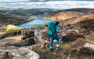 Hiker climbing a cliff edge overlooking a reservoir 