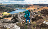 Hiker climbing a cliff edge overlooking a reservoir 