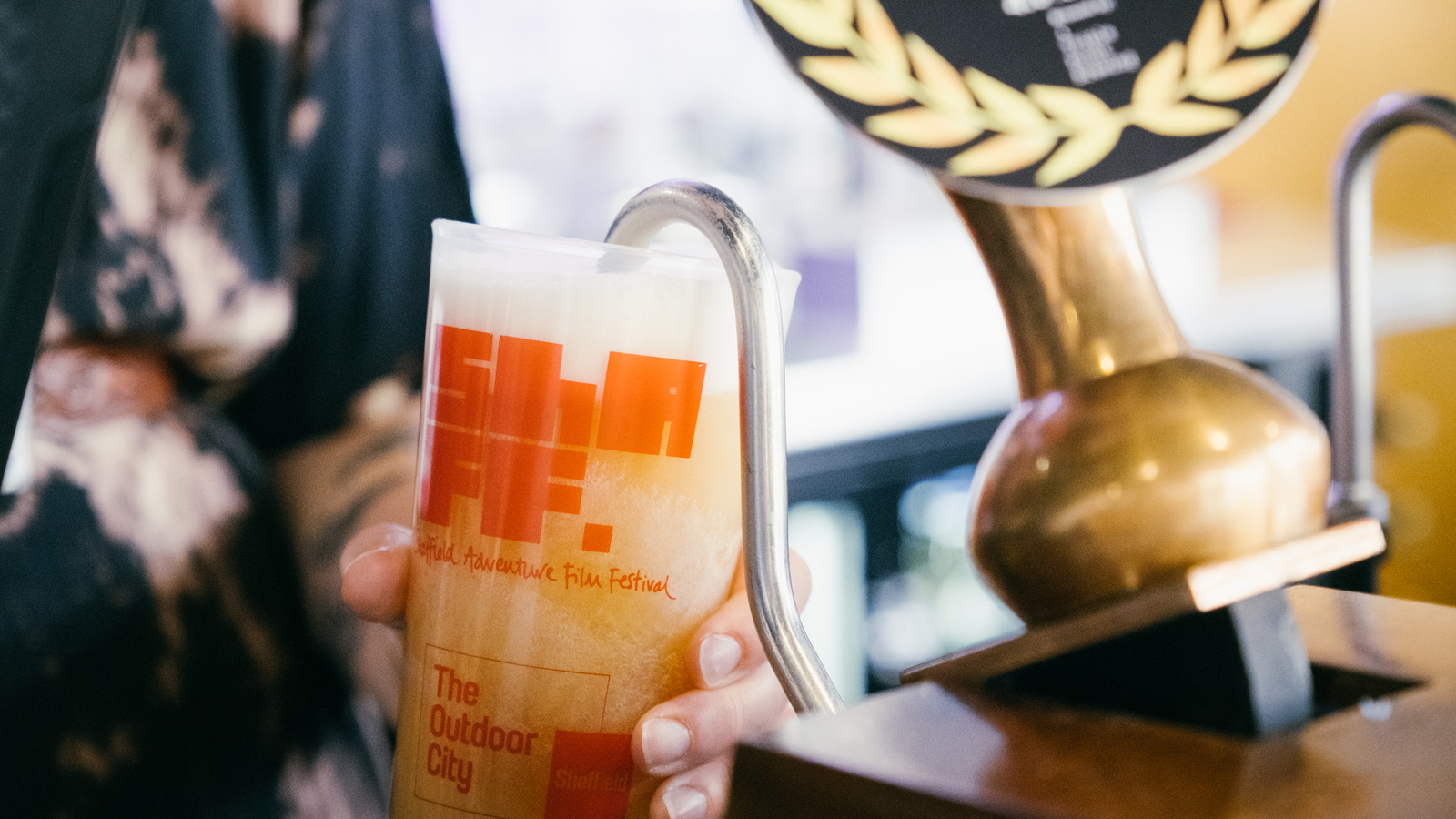 Close up of a ShAFF branded ale being poured into a ShAFF branded pint glass