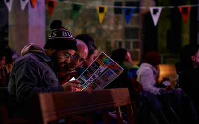 An audience member leans in to read the ShAFF programme in his hands, while waiting in a dimly lit cinema for the film to start
