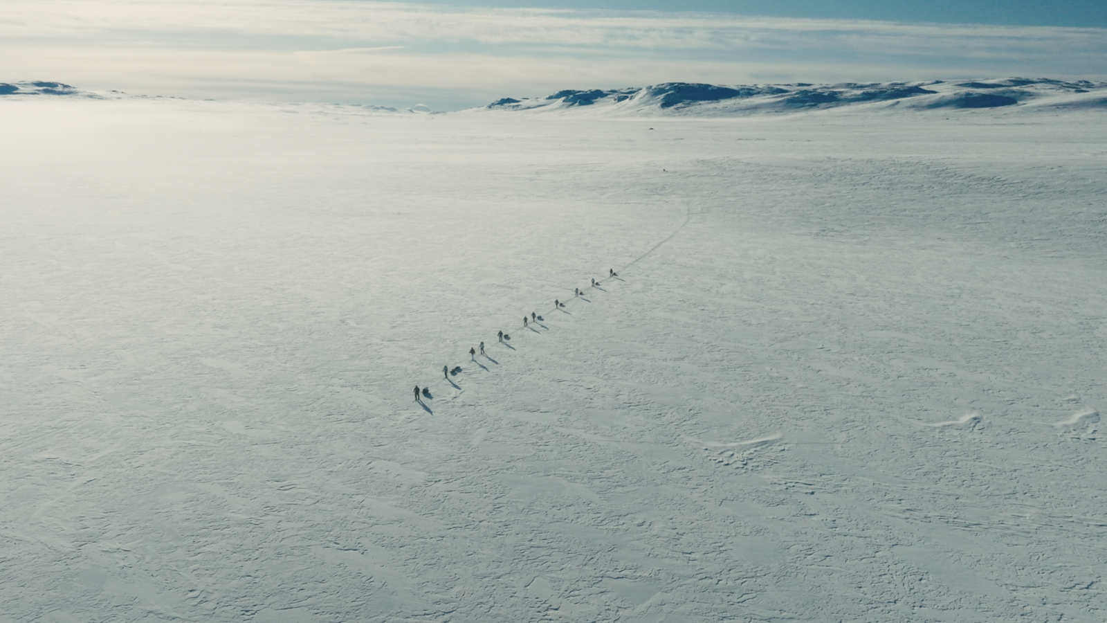 11 skiers crossing an icy plateau