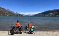 Miriam (Mim) and Roy on completion of the cycle tour in Queenstown at the side of a lake wearing t-shirts with all the babies' names on that the film is dedicated to 