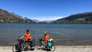 Miriam (Mim) and Roy on completion of the cycle tour in Queenstown at the side of a lake wearing t-shirts with all the babies' names on that the film is dedicated to 