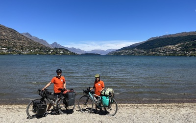 Miriam (Mim) and Roy on completion of the cycle tour in Queenstown at the side of a lake wearing t-shirts with all the babies' names on that the film is dedicated to 