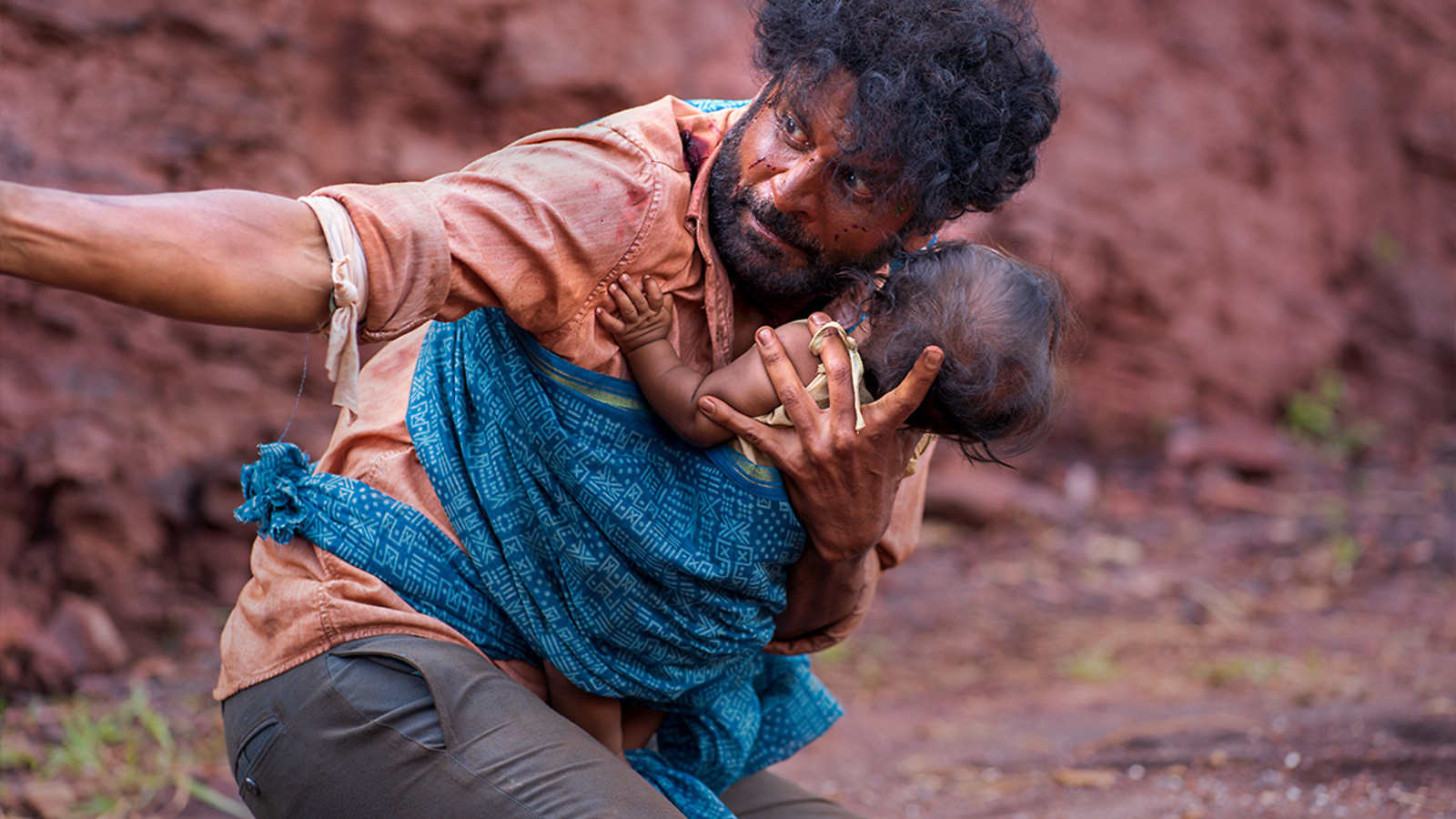 Dasru, bloodied and panicked, cradles his baby in a scene from JORAM