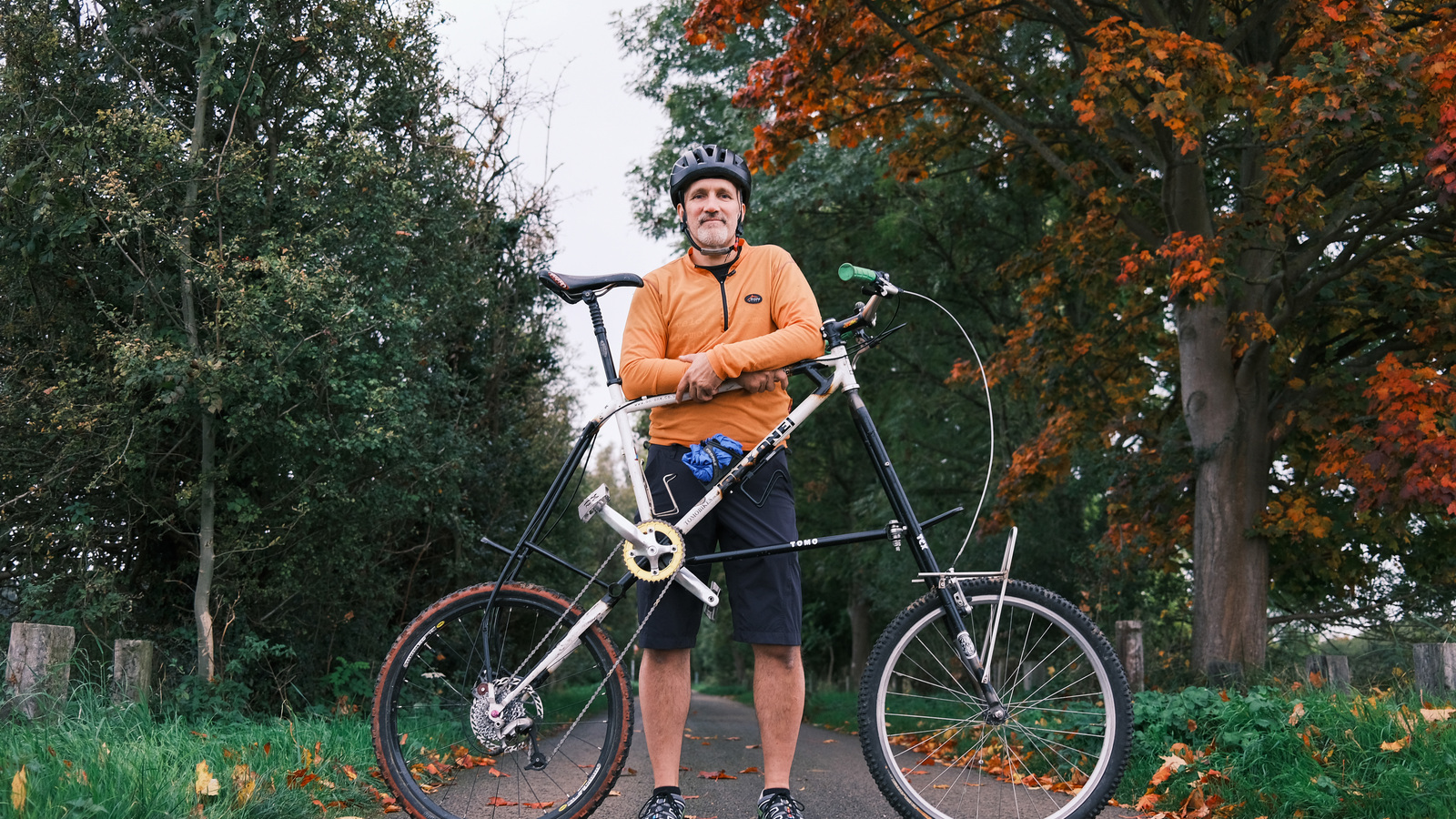 Jon stands behind his tall bike on a cycle path