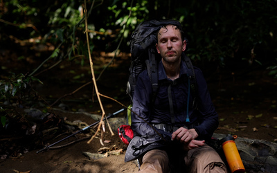 Exhausted man sits in a river in the jungle in Panama