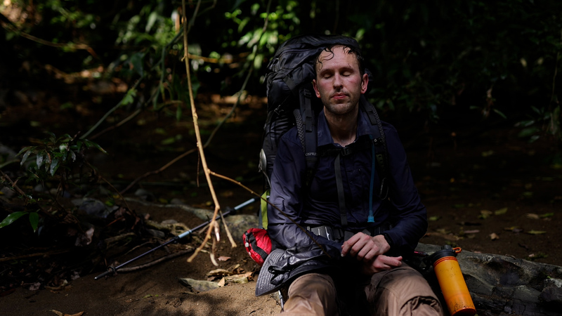 Exhausted man sits in a river in the jungle in Panama
