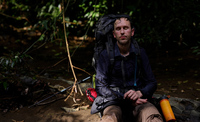 Exhausted man sits in a river in the jungle in Panama