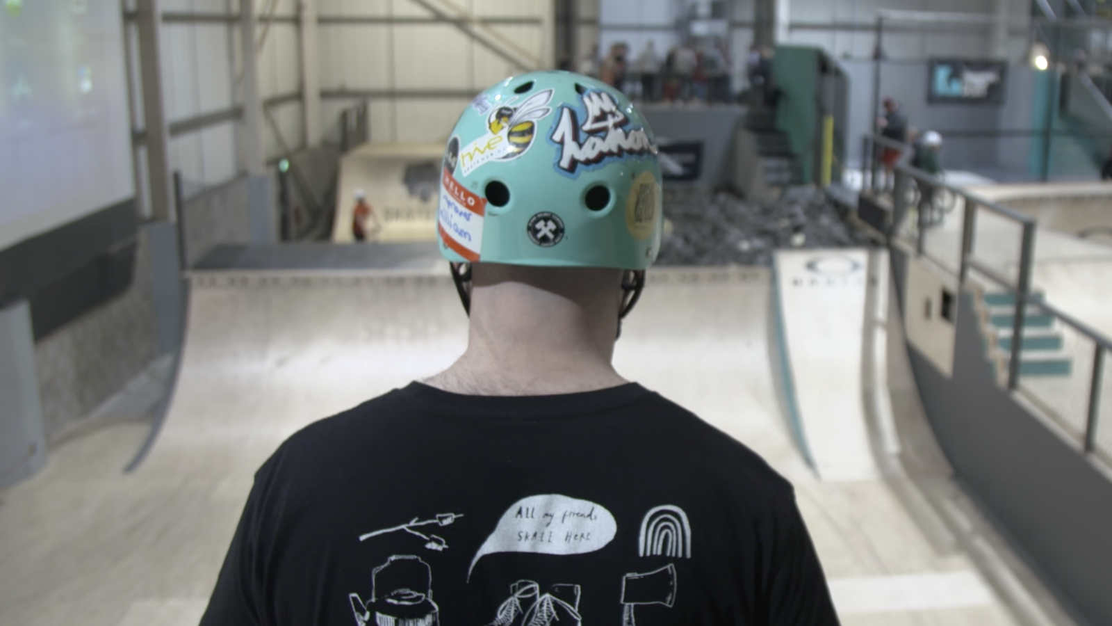 A rollerskater looking down a big ramp into a foam brick pit. Their t-shirt says 'all my friends skate here'