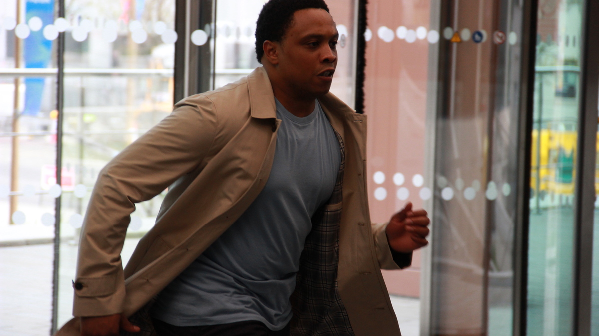 Daniel is running through the entrance of an office building in a still from DEAD WHISTLE STOP.