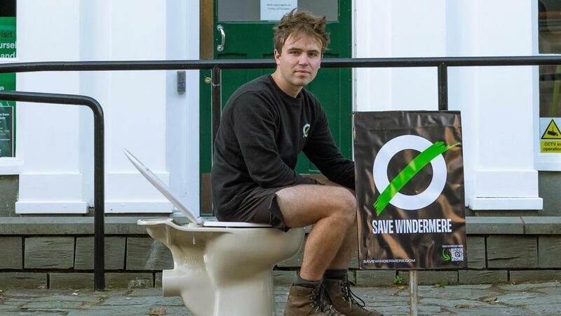 Matt Staniek is sat on a toilet outside United Utilities Information Centre, the company that is polluting Lake Windermere