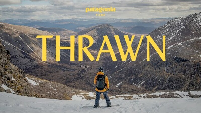 A snowboarder in a yellow jacket looks out onto a mountainous view. The text onscreen reads "Patagonia Presents Thrawn"