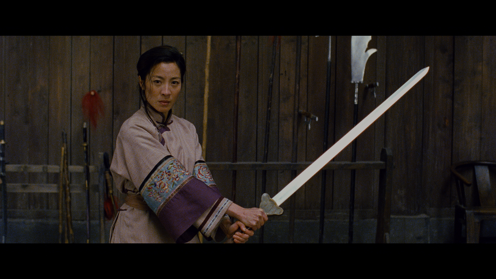 In a still from Crouching Tiger Hidden Dragon, a person holds a samurai sword in their hands.