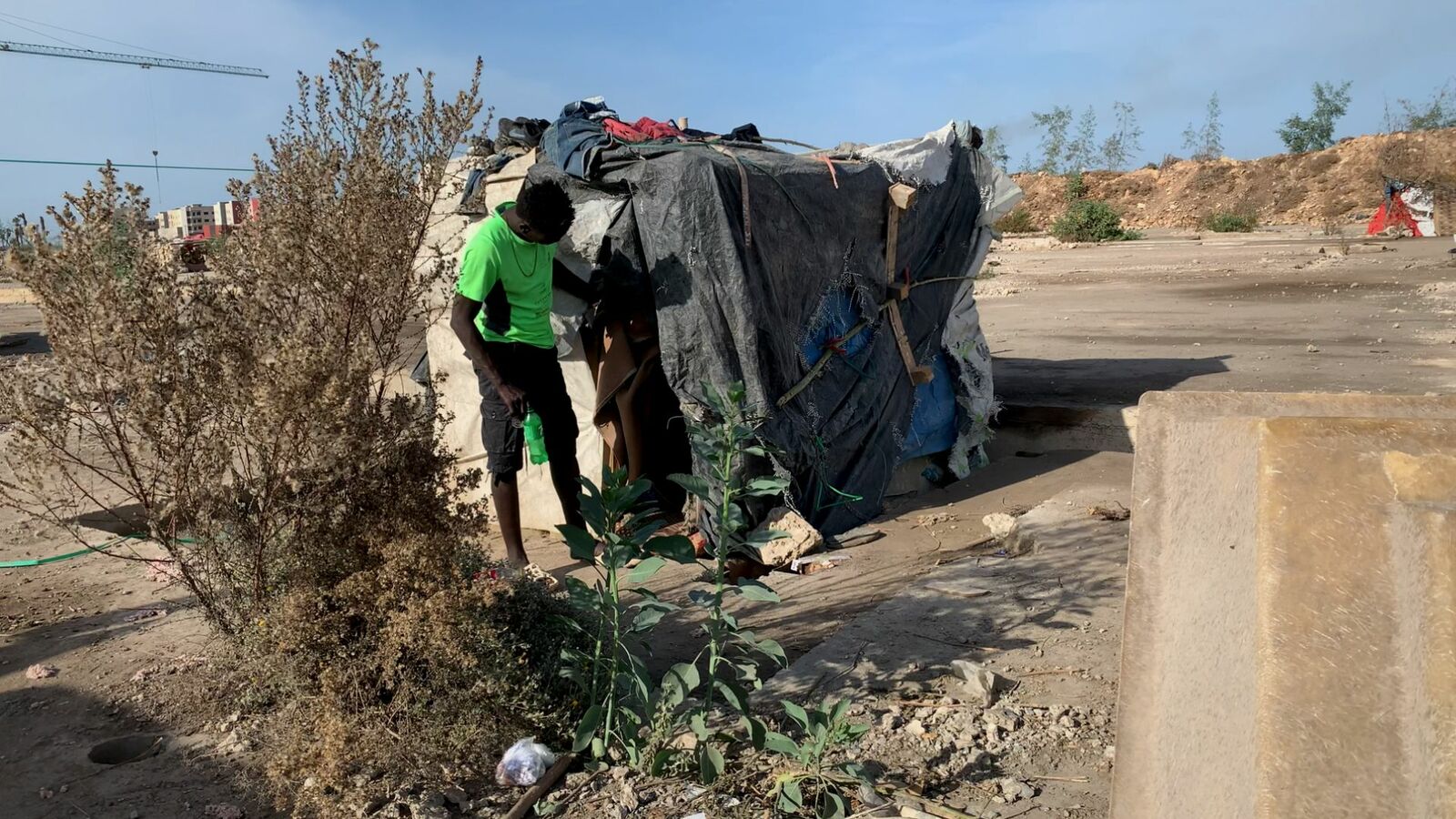 Ayman, a young refugee from Sudan, outside his shelter.