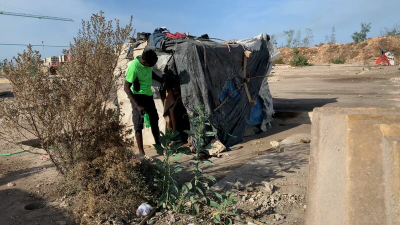 Ayman, a young refugee from Sudan, outside his shelter.