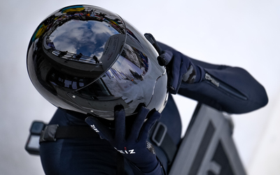 Athlete adjusts her helmet in the final preparations before she drops in on her sled.