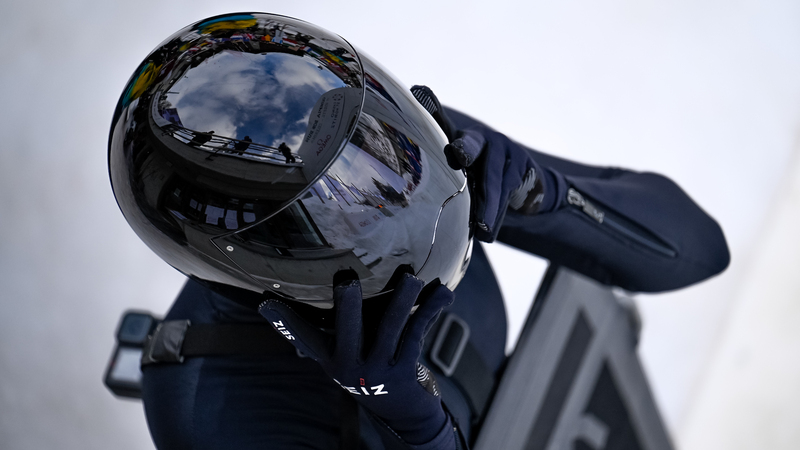 Athlete puts on her helmet just before she drops in on her sled.