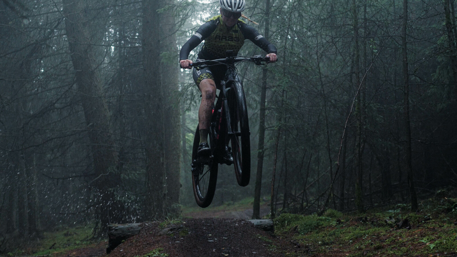 Mountain biker mid air riding through the woods.