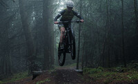 Mountain biker mid air riding through the woods.