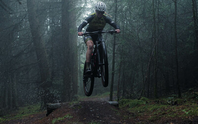 Mountain biker mid air riding through the woods.