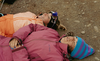 Two runners lying on the ground in the Icelandic desert.