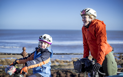 Cyclists, mother and young daughter, smiling with their bikes. 