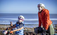 Cyclists, mother and young daughter, smiling with their bikes. 