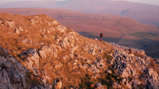 Fell runner Sonny Ashton-Fitch ascends Tow Fell with Ingleborough in the background, North Yorkshire.
