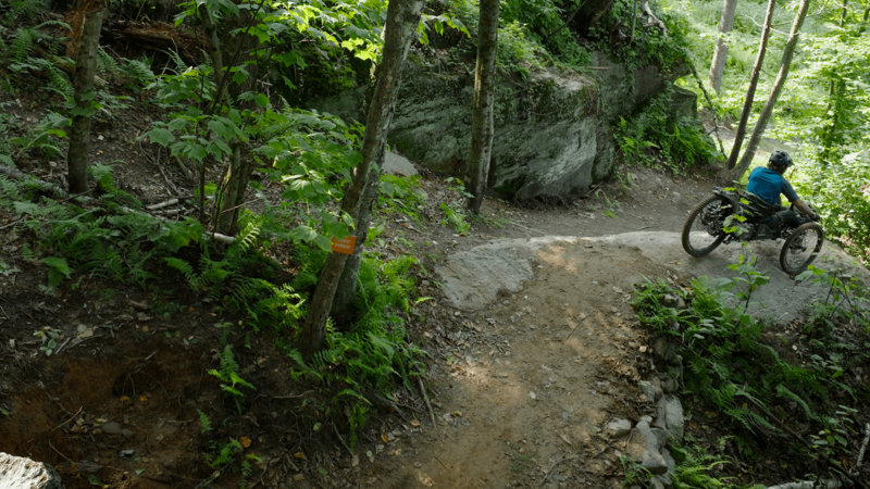 Adaptive Rider Greg Durso at the top of a steep roll at world's first fully adaptive trail network, the Driving Range. 