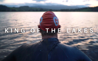 Hector Pardoe, an Olympic open water swimmer, sits, looking out over the final lake as the sun sets. Title reads, "King of the Lakes"