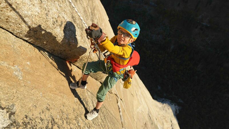 8yr old climber, Jackson Houlding, hangs from a rope as he jumars up the sheer rock face of El Capitan.