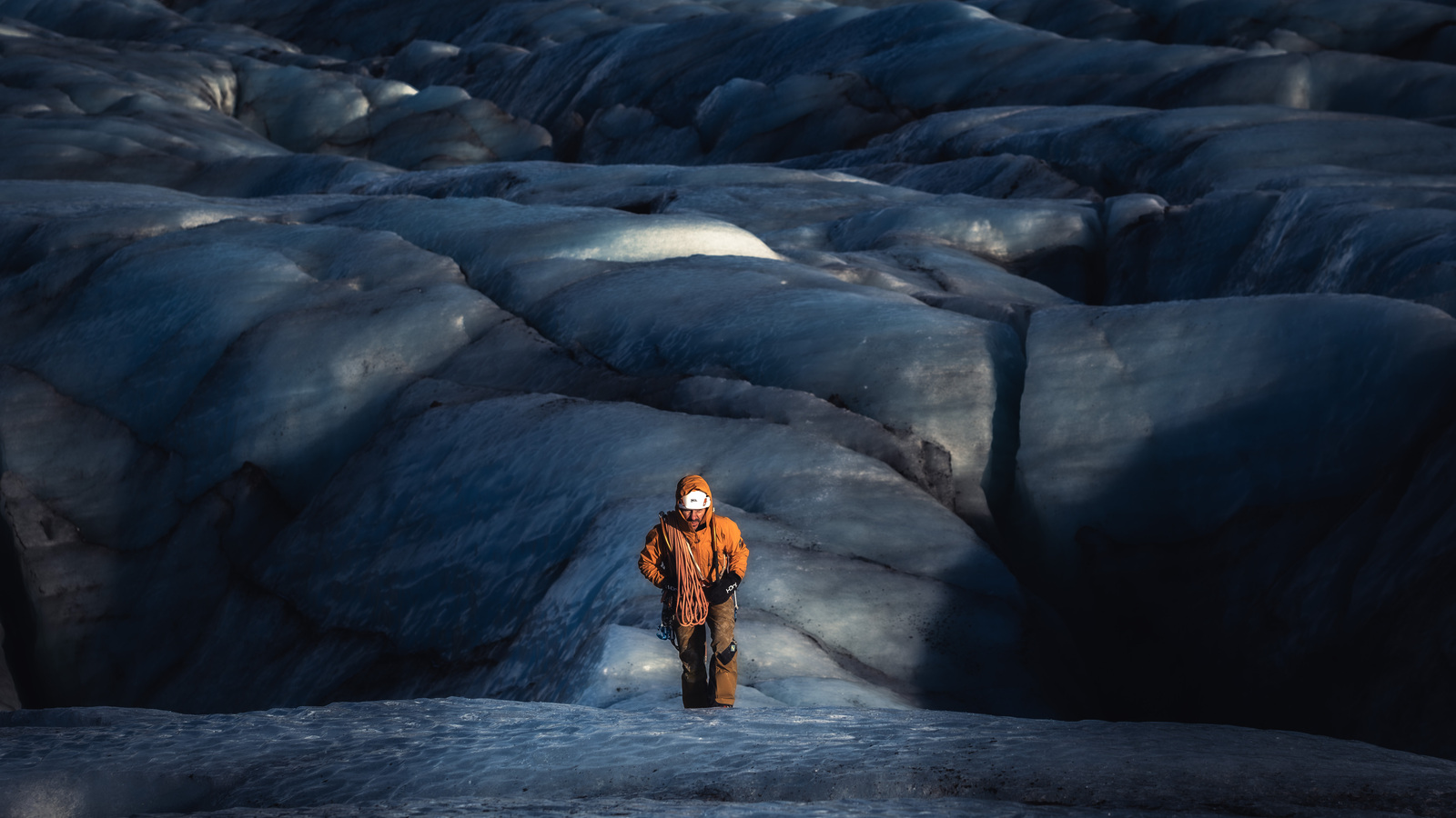Solo climber walking towards camera with rolling glaciers behind