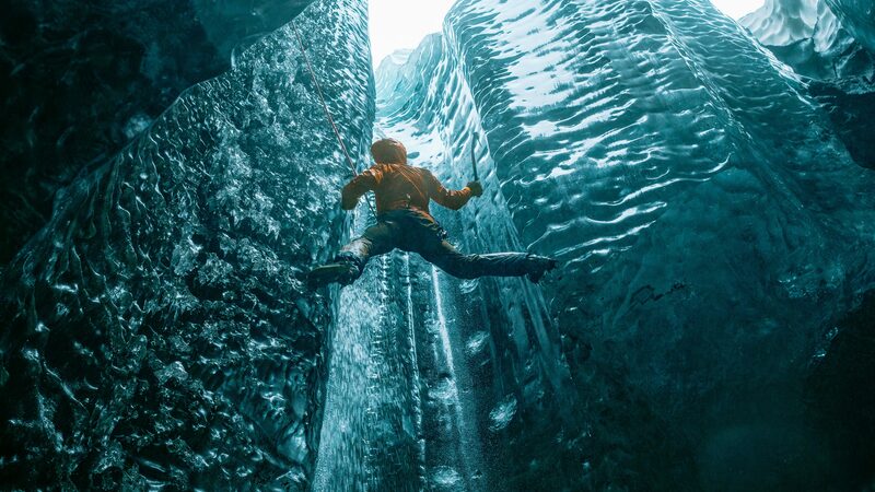 Climber leading on ice axes within a glacier