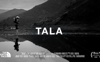 Fernanda Maciel and her water reflection running close to a lake with mountains behind.