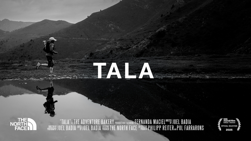 Fernanda Maciel and her water reflection running close to a lake with mountains behind.