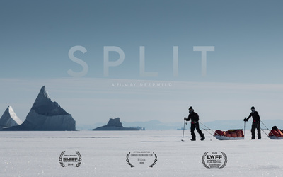 Bright arctic scene with two split boarders pulling pulks in front of distant icebergs frozen into the ice. One is in motion, the other is standing still.