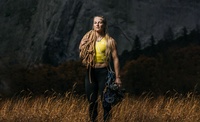 Geared up, professional climber Emily Harrington standing in front of a huge stone wall.
